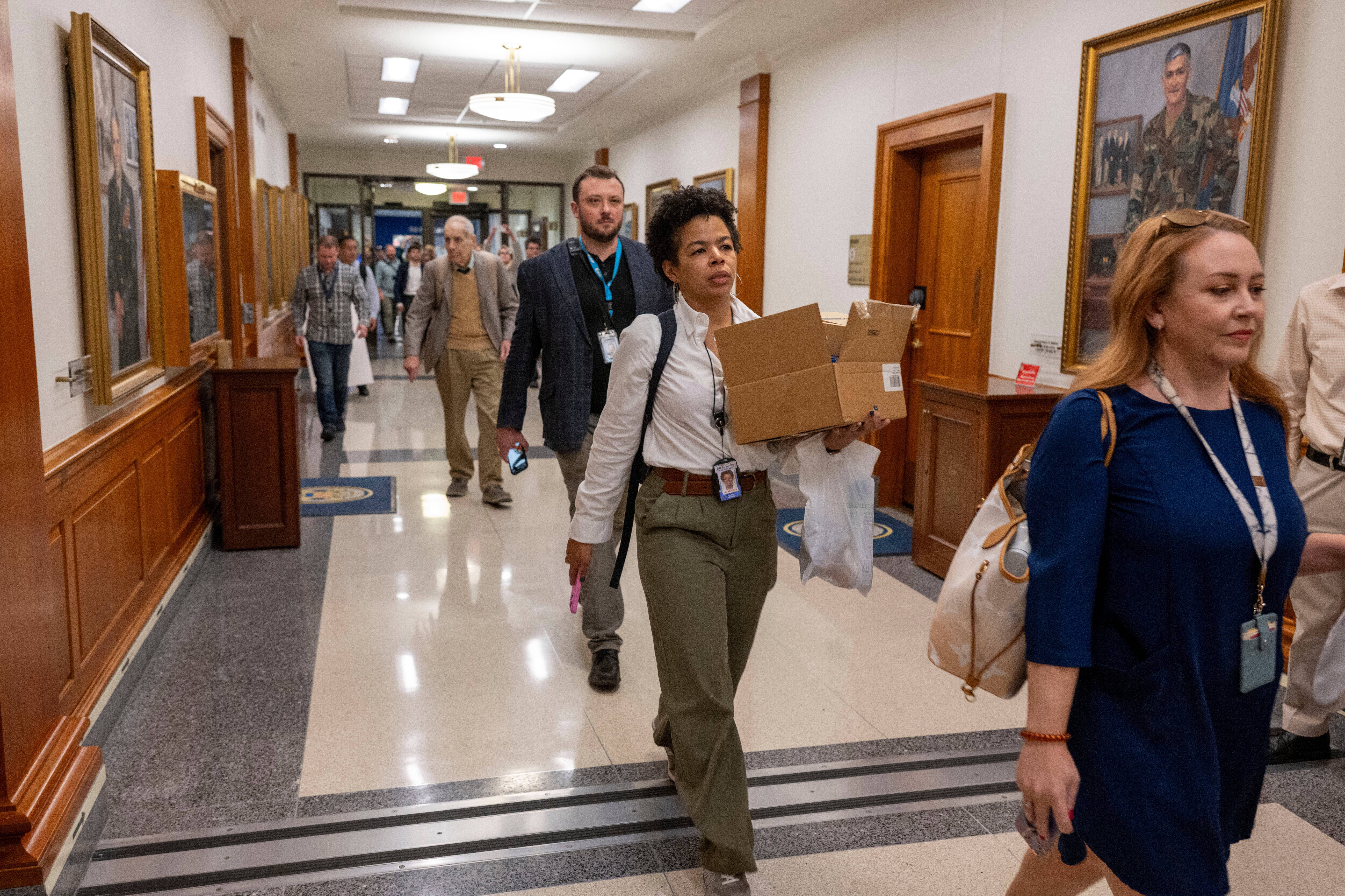 Members of the Pentagon press corps walk out of the Pentagon as a group after turning in their press credentials on Wednesday, Oct. 15, 2025. On Thursday, <em>The New York Times</em> sued the Defense Department and Secretary Pete Hegseth over its new media policy.